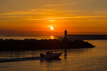 Fototapeta premium Portugal,Faro の漁港を日の出と共に出ていく漁師の船 / Portugal の最南端地方の町Faroに続く漁港を夜明けと共に出港する漁師の舟です。
