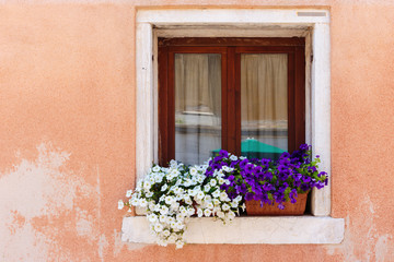 Fototapeta na wymiar Window in an old house decorated with flower pots and flowers