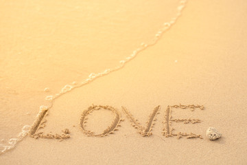 love handwritten on a sandy beach