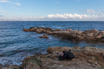 Tourist on a cliff photographing the sea, Cote d'Azur, France
