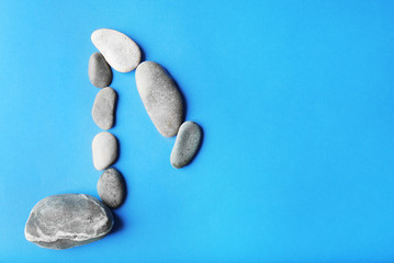 Music note sign made of stones on blue background