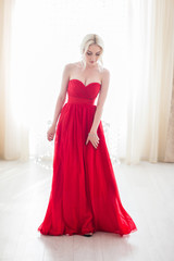 Beauty Blond model woman in evening red dress.