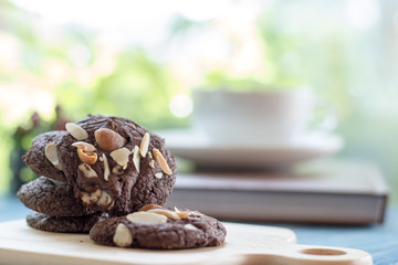 Chocolate cookie on blue wooden table and green garden background.