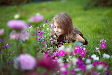 Obraz na płótnie Canvas Girl sitting on grass and smelling flowers.