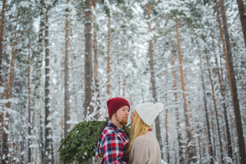 young couple with fir twigs walk in the winter woods