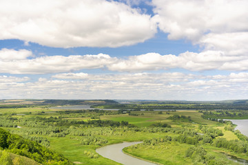 Blue sky with clouds over a green river valley
