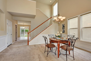 Beige dining room interior with high ceiling and staircase