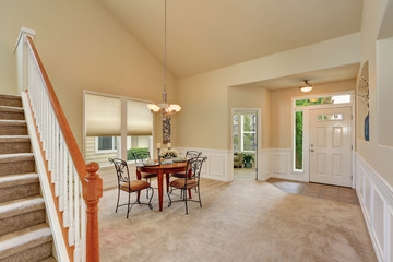 Beige dining room interior with high ceiling and staircase