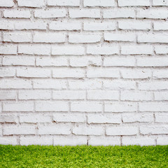 Green grass over brick wall background.