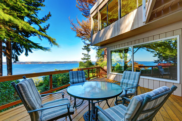 Glass top table with striped chairs on a wooden walkout deck.