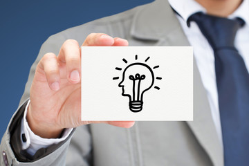 Businessman showing card with sign of light bulb.