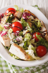 Sliced grilled chicken with mixed salad and tomatoes close-up. vertical