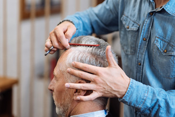 Hairdresser combing hair of old man