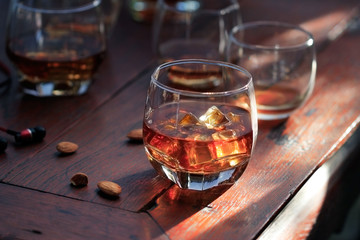 Whiskey bourbon in a glass with ice on wooden table background