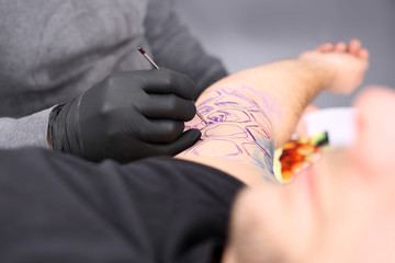 Tatuaż,tatuator wykonuje tatuaż na ręce mężczyzny.