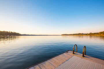 Fototapeta premium Wooden pier on lake sunset and sky reflection water.