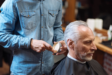 Barber going to style hair of client with gel