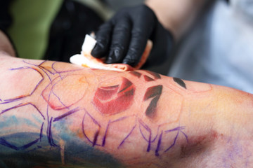 Kolorowy tatuaż. Tatuaż,tatuator wykonuje tatuaż na ręce mężczyzny.