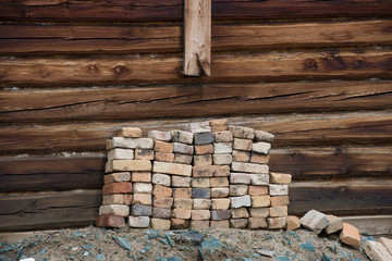 Pile of old bricks on the background wall  a wooden house.