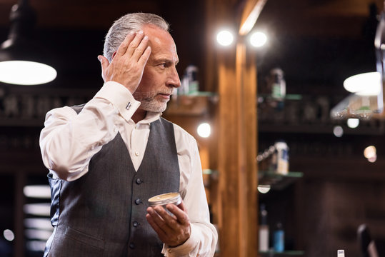 Senior businessman with hair gel in front of mirror