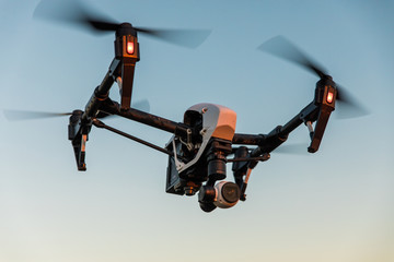 Drone-quadrocopter with camera hovers on the blue sky/Drone flying in the sky