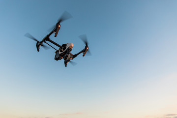Drone-quadrocopter with camera hovers on the blue sky/Drone flying in the sky