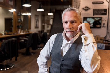 Old man sitting at bar counter and looking forward