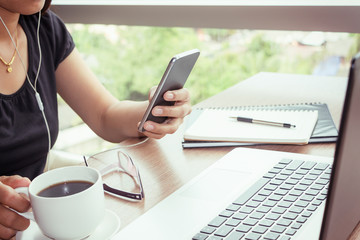 Close Up of woman hands using mobile phone and laptop computer with blank copy space screen for your advertising text message or content business in the Vintage effect.