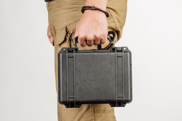 guard hand in handcuffs close up holding case with money 