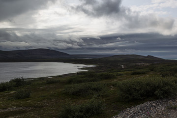 Storm clouds over the green valley and the lake, highlands. Arctic summer, the tundra, Norway.