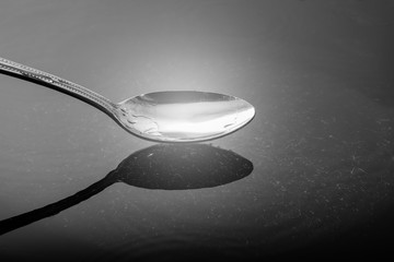 Stainless steel spoon above the water reflection.