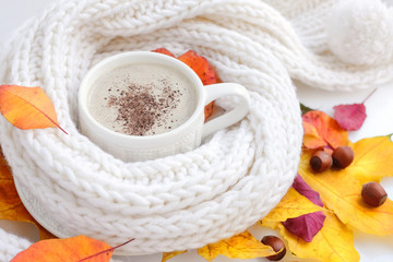 Fototapeta na wymiar Autumn leaves, hot cup of coffee and a warm scarf on white background
