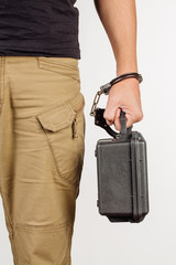 guard hand in handcuffs close up holding case with money isolated in white background