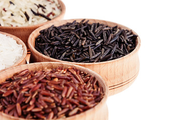 Red, black and white rice close-up in wood bowls on white background. Isolated. Rice texture background.