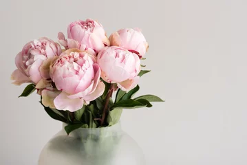 Washable wall murals Peonies Close up of pink peonies in glass jar against neutral background with copy space to right (selective focus)