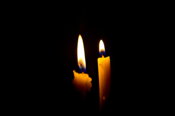 One light candle burning brightly in the black background
