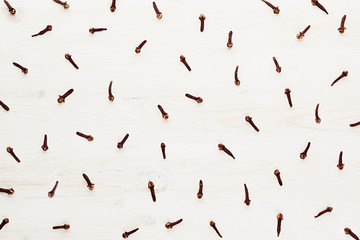 Cloves spice on white wood background. Christmas decorative pattern.