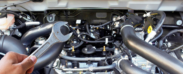 Obraz premium Hand with wrench checking car engine