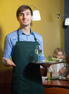 portrait of a waiter holding a tray in his hand in the restauran