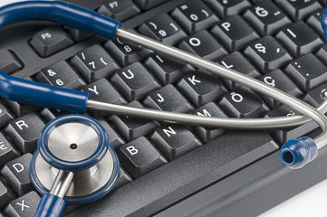 Stethoscope resting on computer keyboard - online medical support concept.  