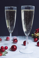 Christmas illuminations with champagne glass. Glasses of champagne with bubbles on snow. Black background