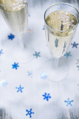 Christmas illuminations with champagne glass. Glasses of champagne with bubbles on snow. Blue snowflake