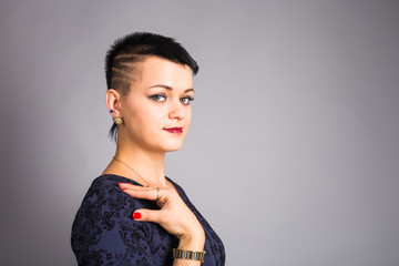 Portrait of young beautiful woman with stylish short haircut over grey background