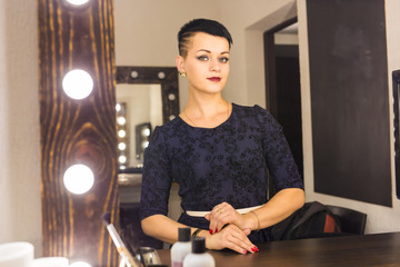 Young woman with short hair looking herself reflection in mirror