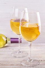 Glasses and bottle of white wine. Grilled dorado fish with vegetables in white plate