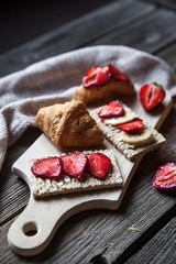 A delicious breakfast of strawberries and bread on wooden background. Fruit, food, sandwiches, cheese. Vintage style.