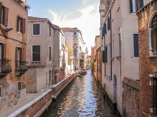 Fototapeta na wymiar Traditional boats on canals of Venice through Venetian alleys. Italian city of Unesco Heritage.