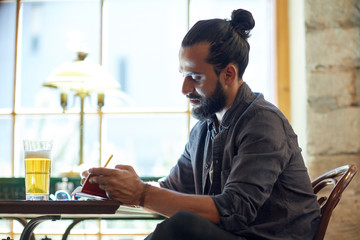 close up of man with beer and notebook at pub