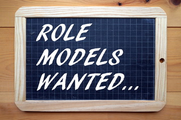The phrase Role Models Wanted in white text on a used blackboard as a call out for people who can...