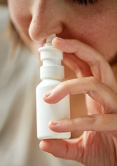 close up of sick woman using nasal spray